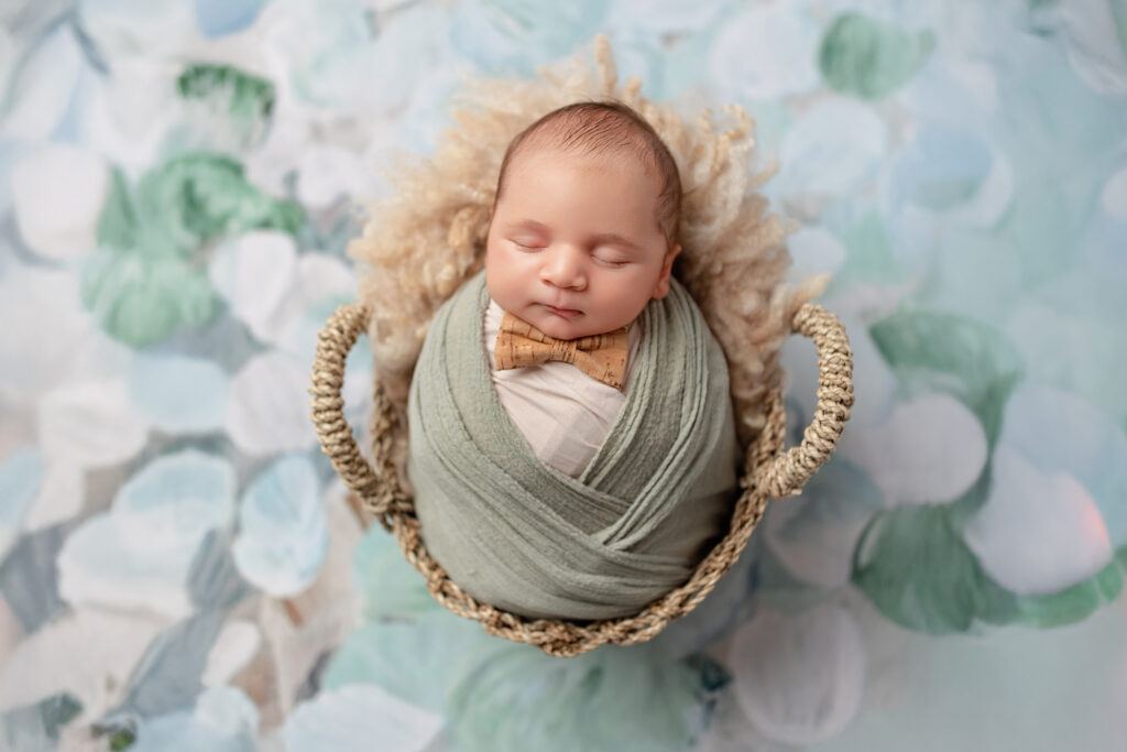 Burlington newborn photographer capturing a baby boy wrapped in soft green tones with a tiny bow tie.