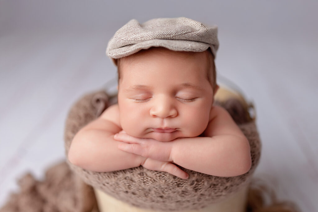 Close-up of a newborn baby boy resting on his hands, photographed by Burlington newborn photographer Tricia at our Oakville studio.