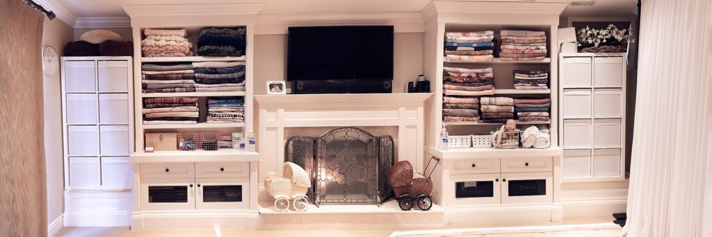 Floor-to-ceiling wall of newborn photography props and blankets, showcasing the extensive variety available in our Oakville studio.