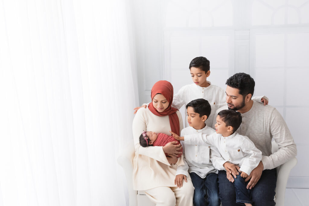 Family portrait with newborn baby girl during a soft, bright studio session.