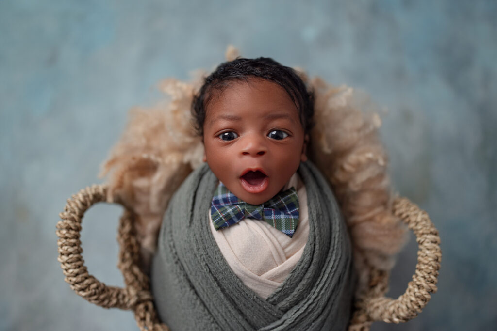 Settling this newborn baby boy wrapped in soft green layers with a sweet yawning expression during his Oakville studio session.