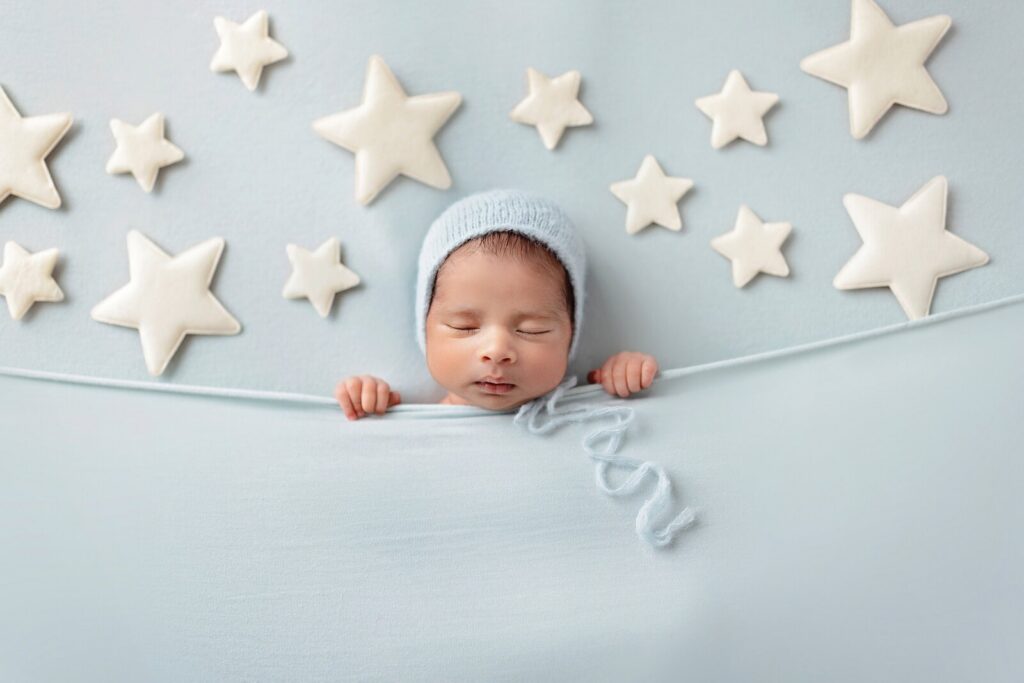 Sleeping newborn in a soft blue setup with stars during a newborn photography Oakville session by McLelland Photography. 