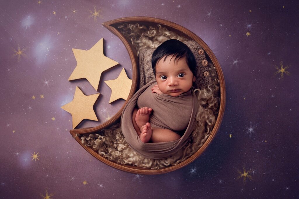 Newborn wrapped on a crescent moon with stars during an Oakville newborn photography session by McLelland Photography. 