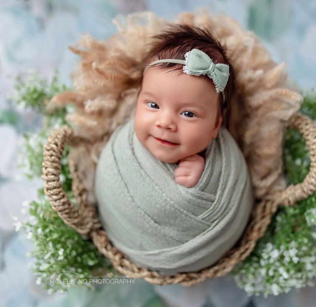 newborn safety training allowed mclelland photography to capture a cute newborn wrapped in a  green blanket