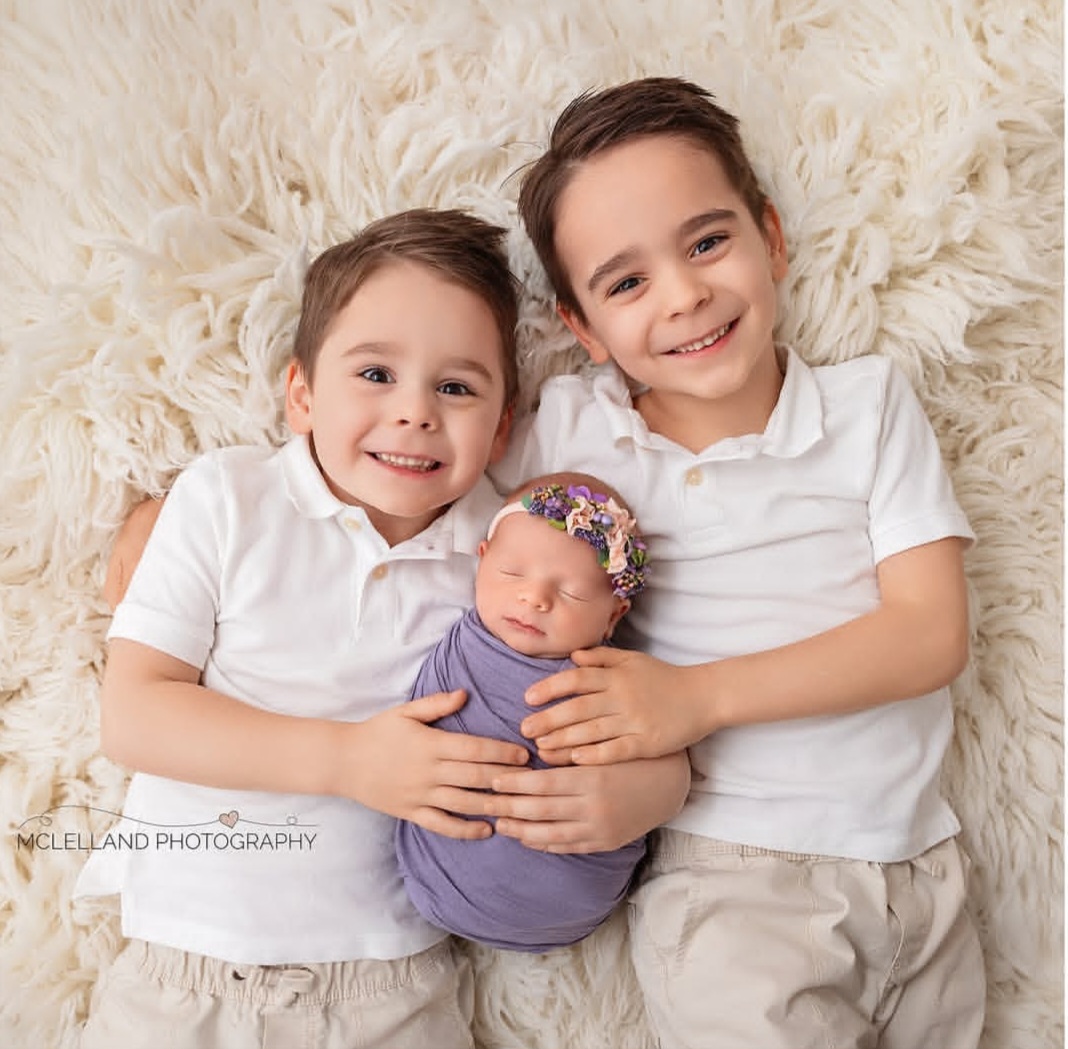 brothers with their newborn sibling during the best time to take newborn photos