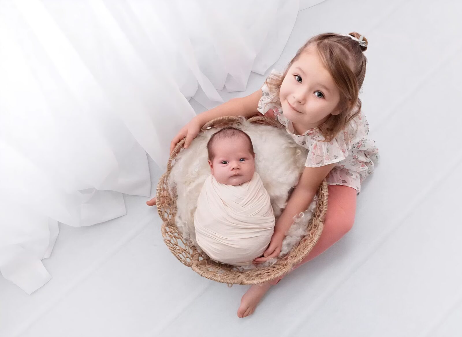 portrait of a sister with her newborn sibling taken at the best time for newborn photos