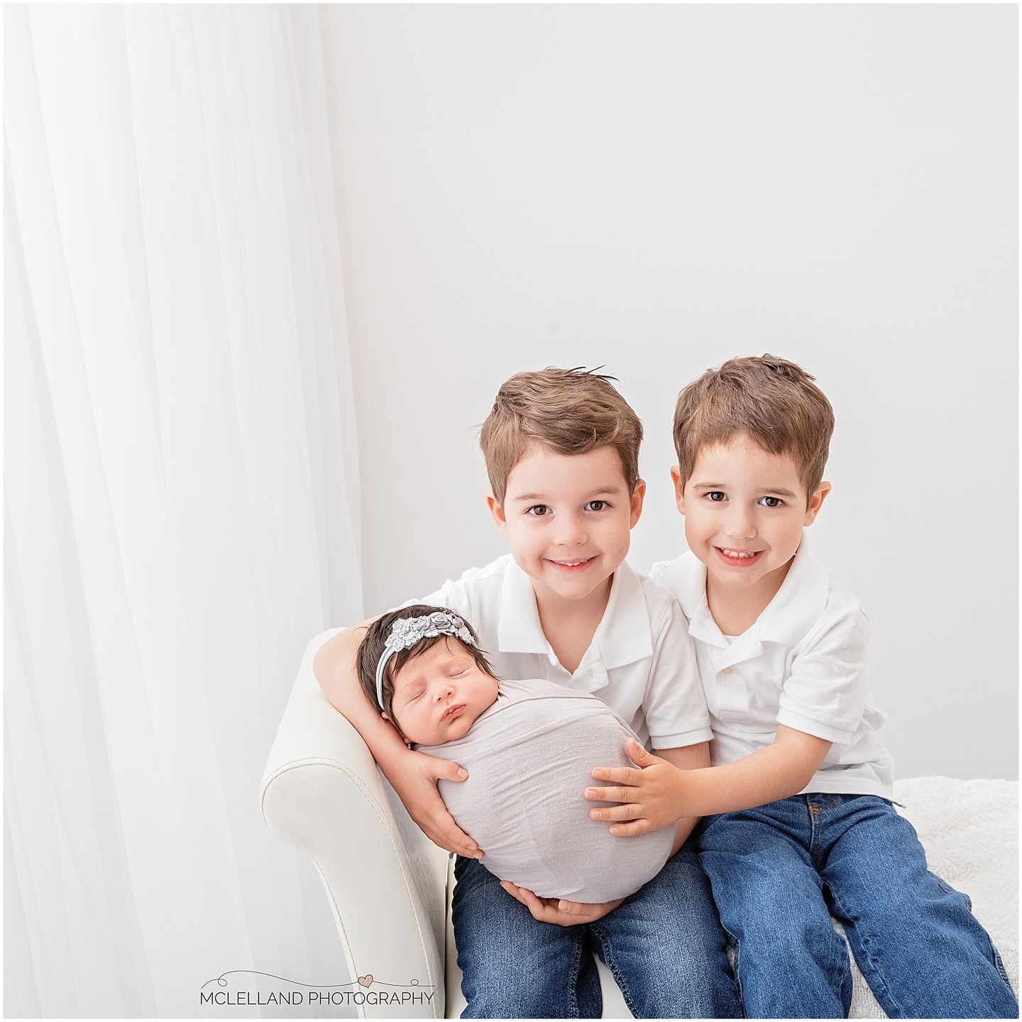 Newborn baby photographed with two older brothers during a professional newborn session