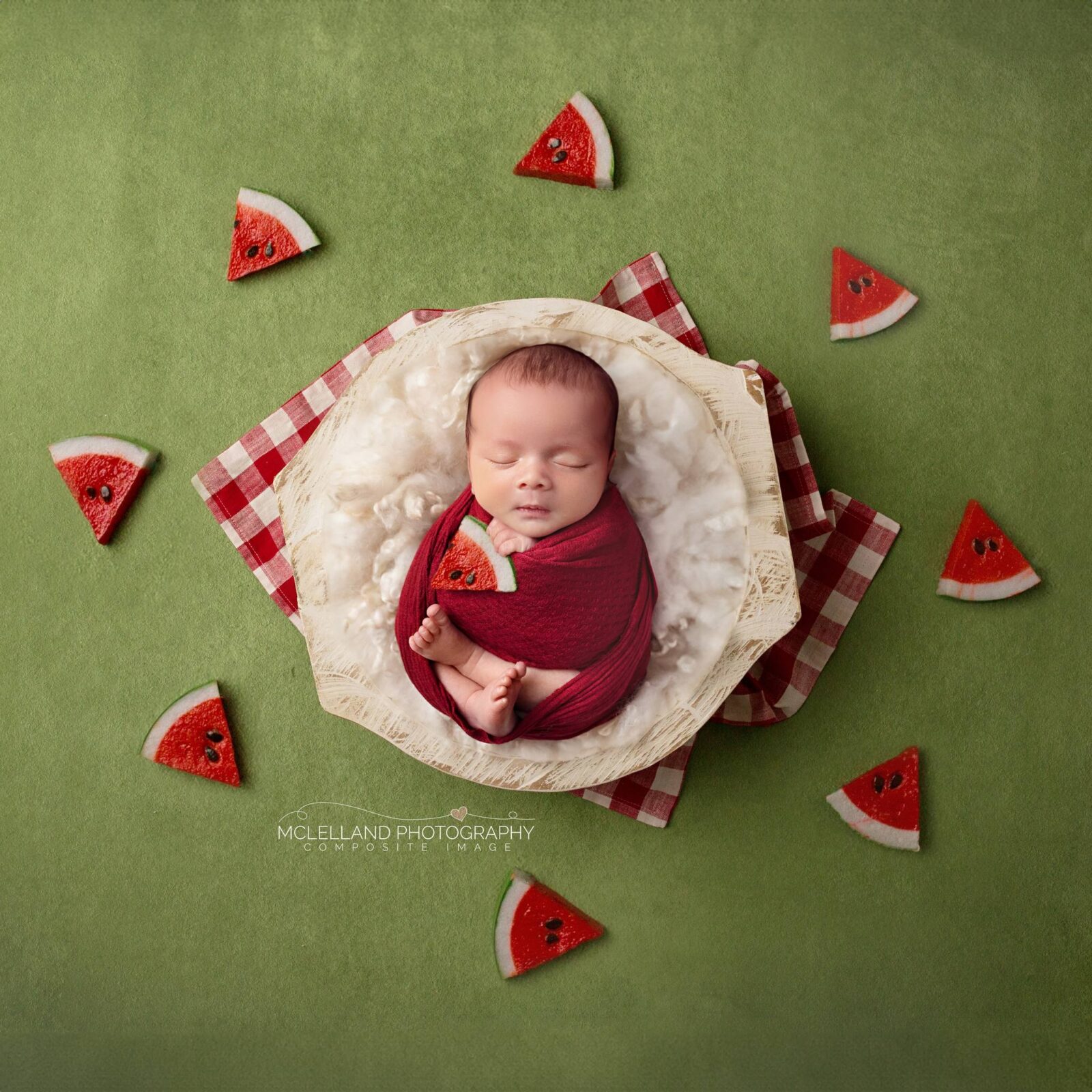 Newborn baby wrapped in red in a professional composite image with a watermelon-themed setup
