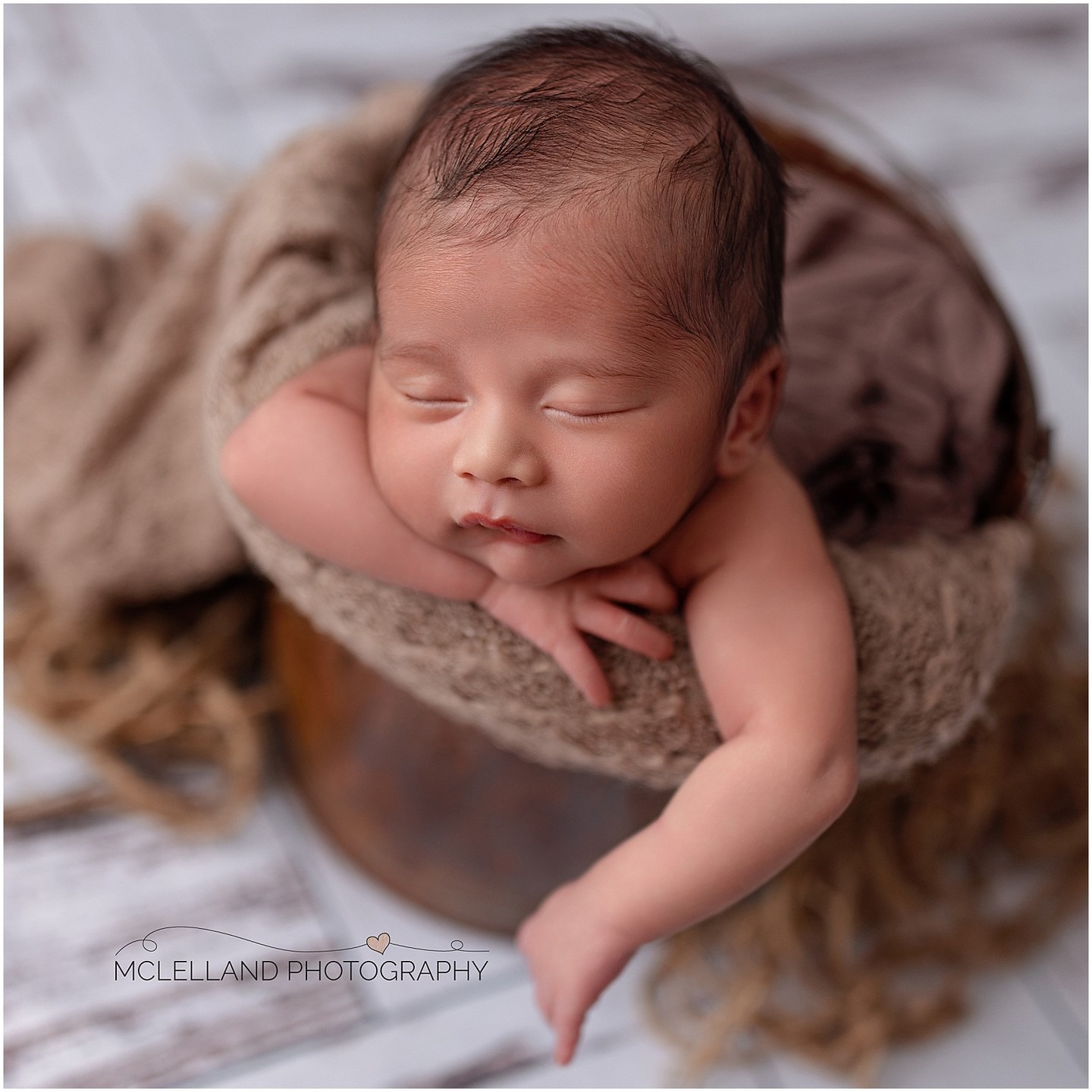 Close-up professional newborn photography portrait of a sleeping baby posed with hands beneath the face