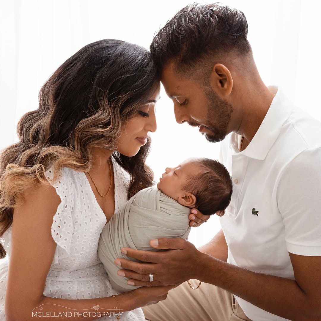 Professional newborn photography portrait of parents holding their sleeping baby
