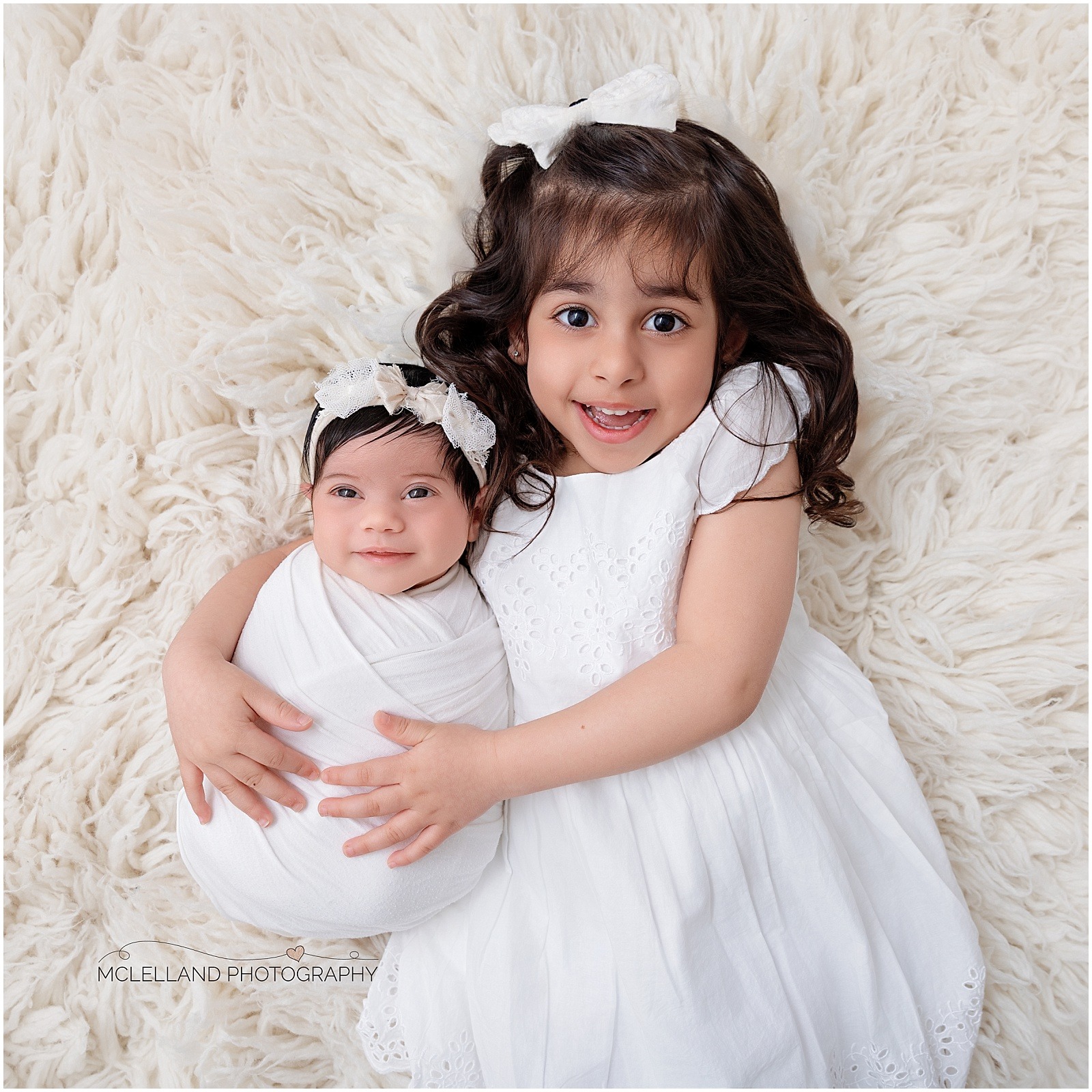 Professional newborn photography portrait of an older sister holding her newborn sibling