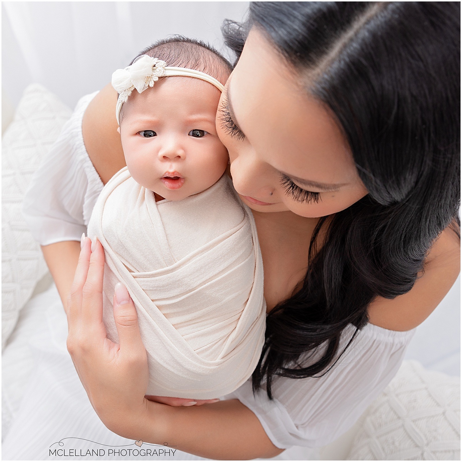 Mother cuddling her awake newborn baby close to her face during a studio portrait